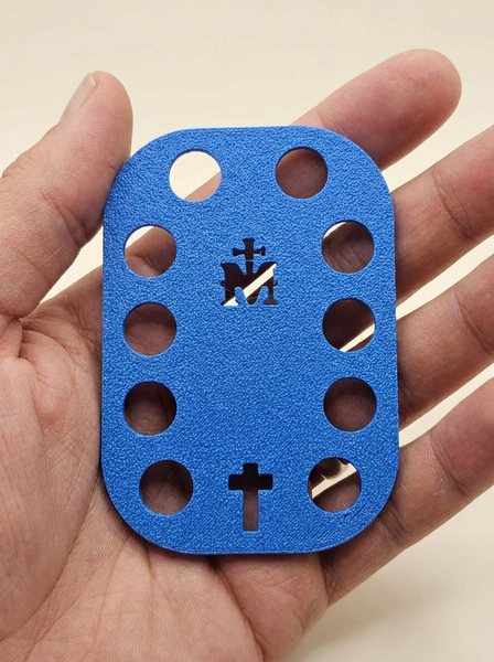 El rosario de bolsillo azul de Almadera en la mano: la M de María arriba, la cruz abajo y diez agujeros alrededor